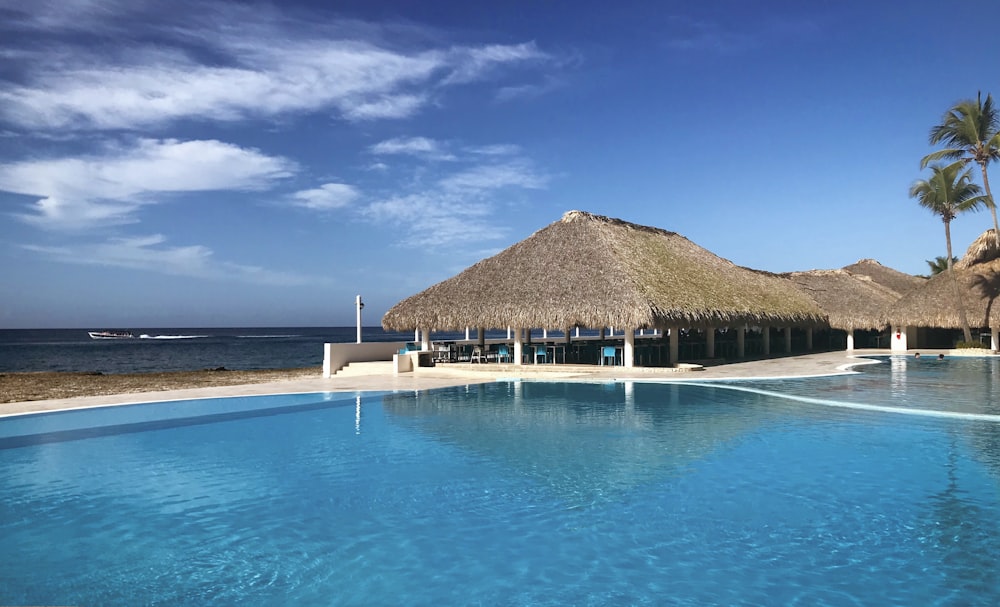 Una gran piscina con techo de paja junto al océano