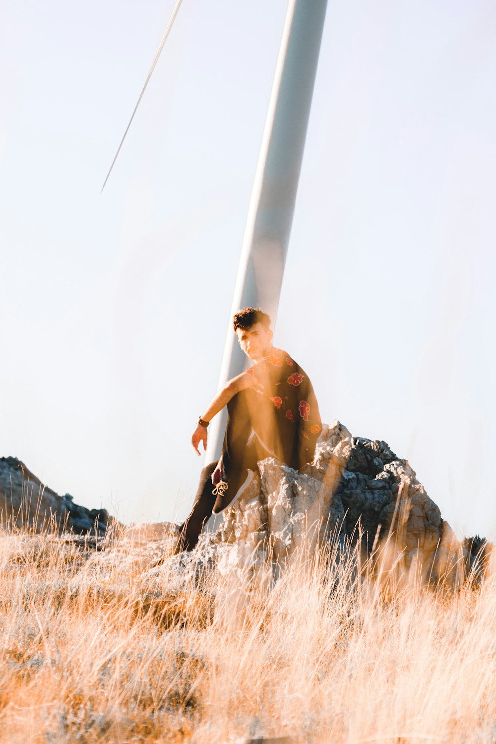 a man sitting on a rock next to a wind turbine