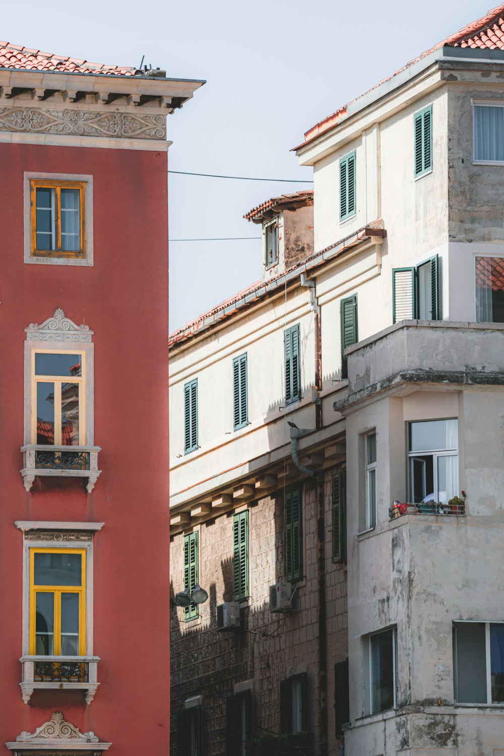 a tall red building with yellow windows next to other buildings