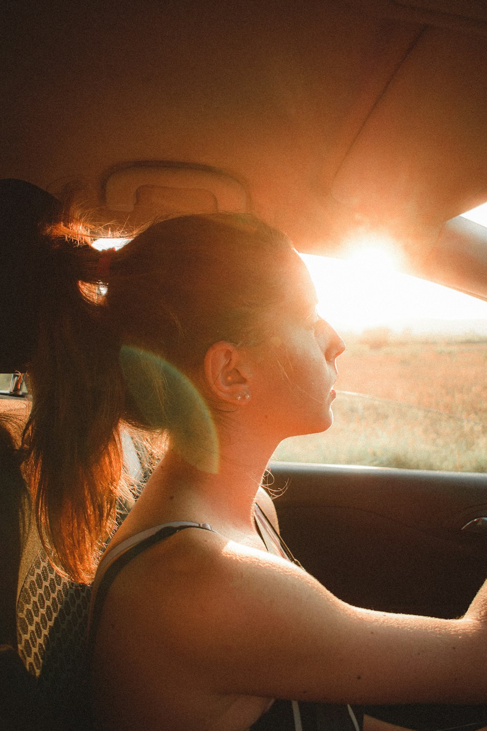 a woman driving a car in the sun