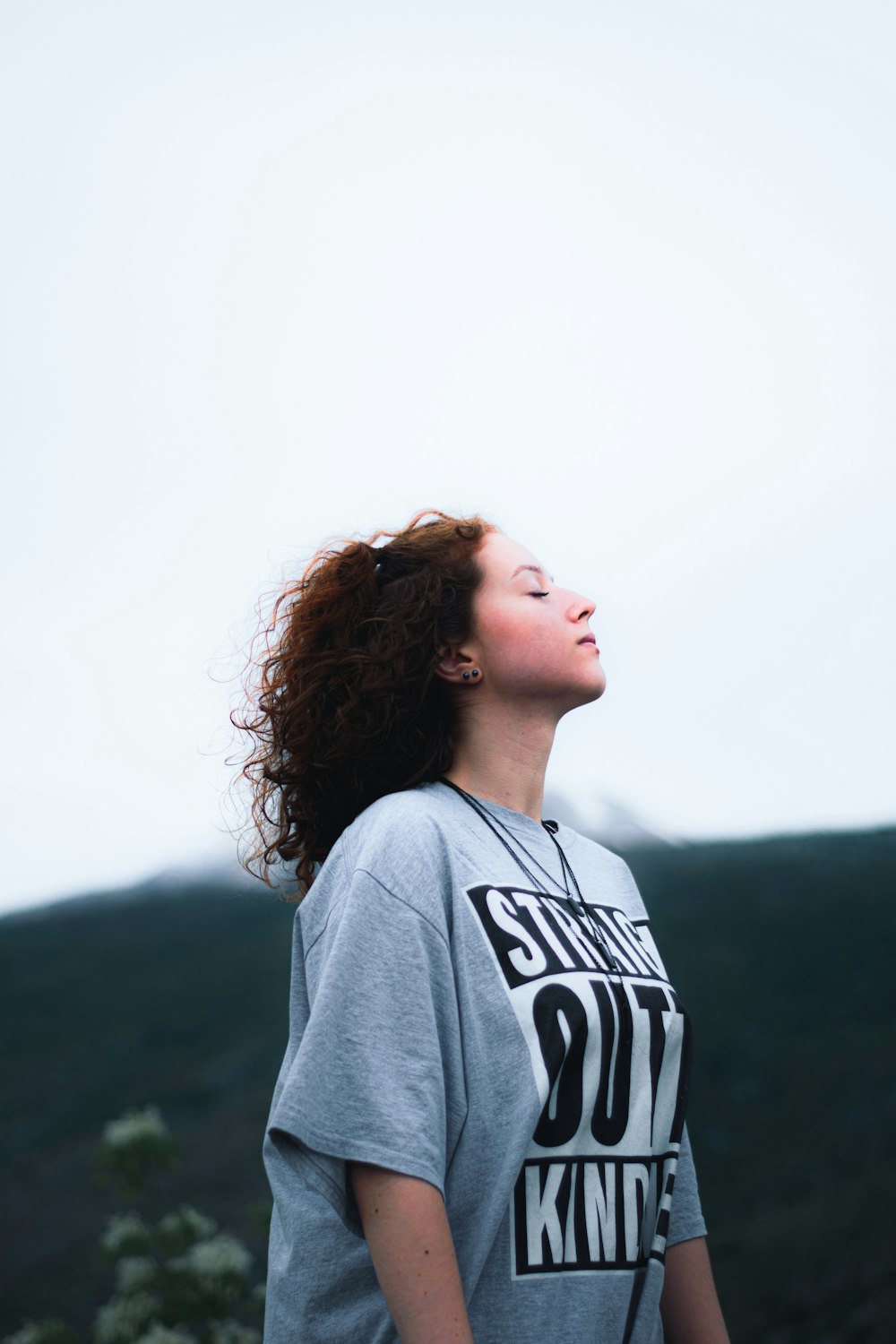 a woman with her eyes closed standing on a hill