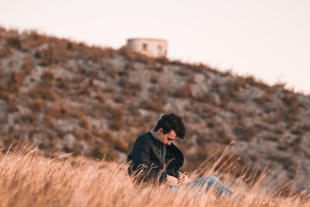 a man sitting in a field looking at his cell phone