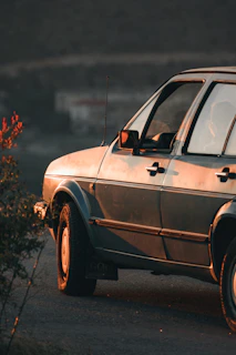 An elegant classic car lined up alongside the Mediterranean coast, bathed in soft evening light.