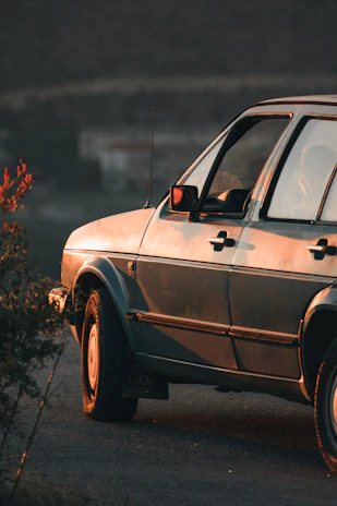 An elegant classic car lined up alongside the Mediterranean coast, bathed in soft evening light.