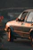 Close-up of a weathered vintage car against a backdrop of rustic wooden beams and soft evening light.