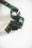 A length of filmstrip is coiled in a loose spiral on a plain, light background. The filmstrip has a glossy appearance with visible perforations along the edges and varying shades of dark, translucent green.