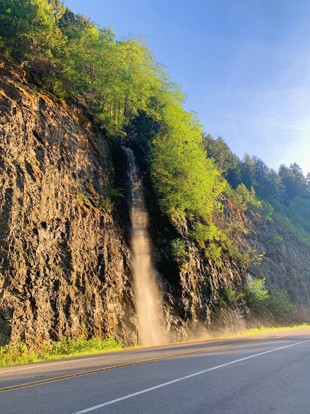 a car driving down a road next to a waterfall
