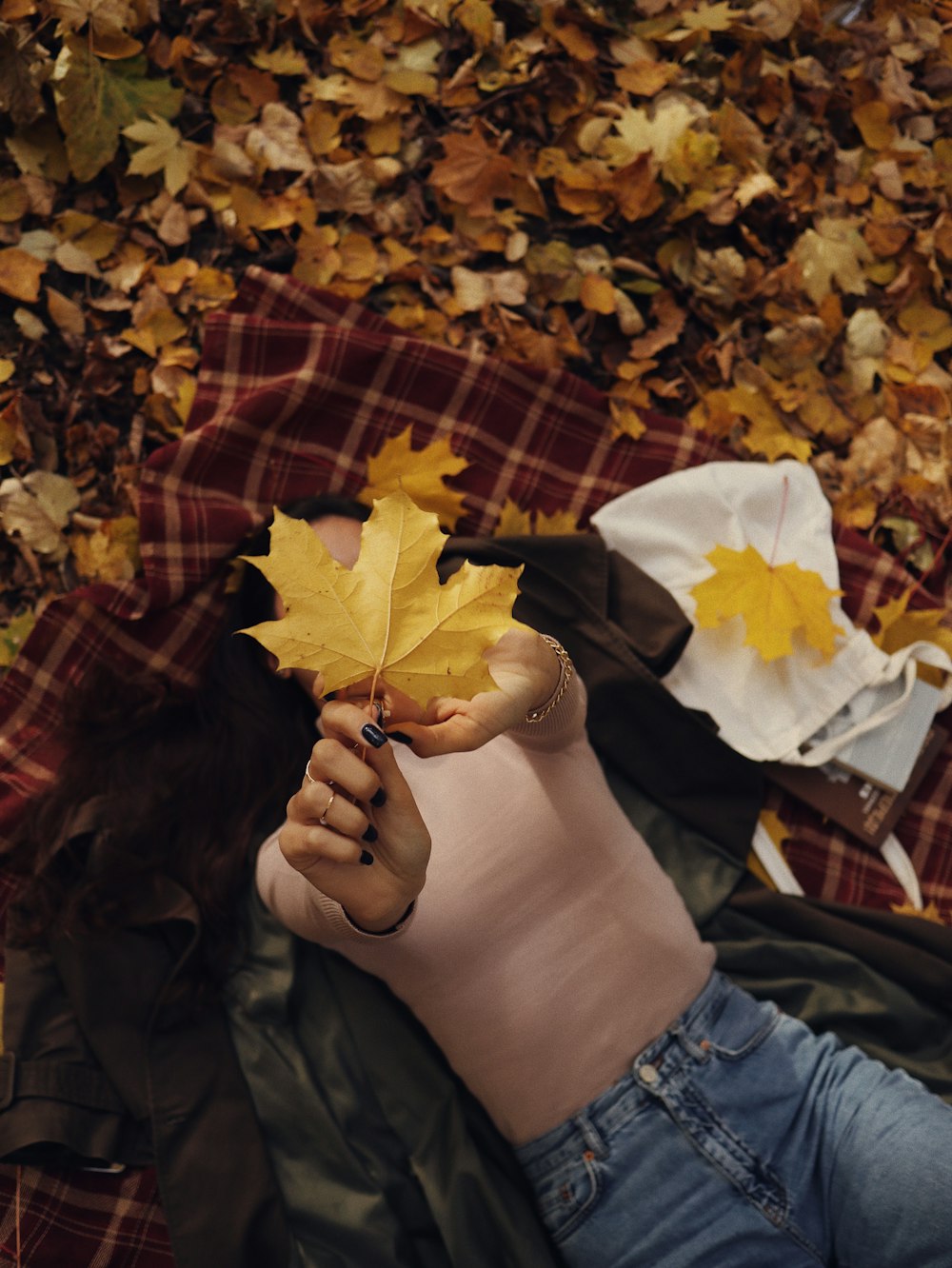 a woman laying on the ground with a leaf in her hand