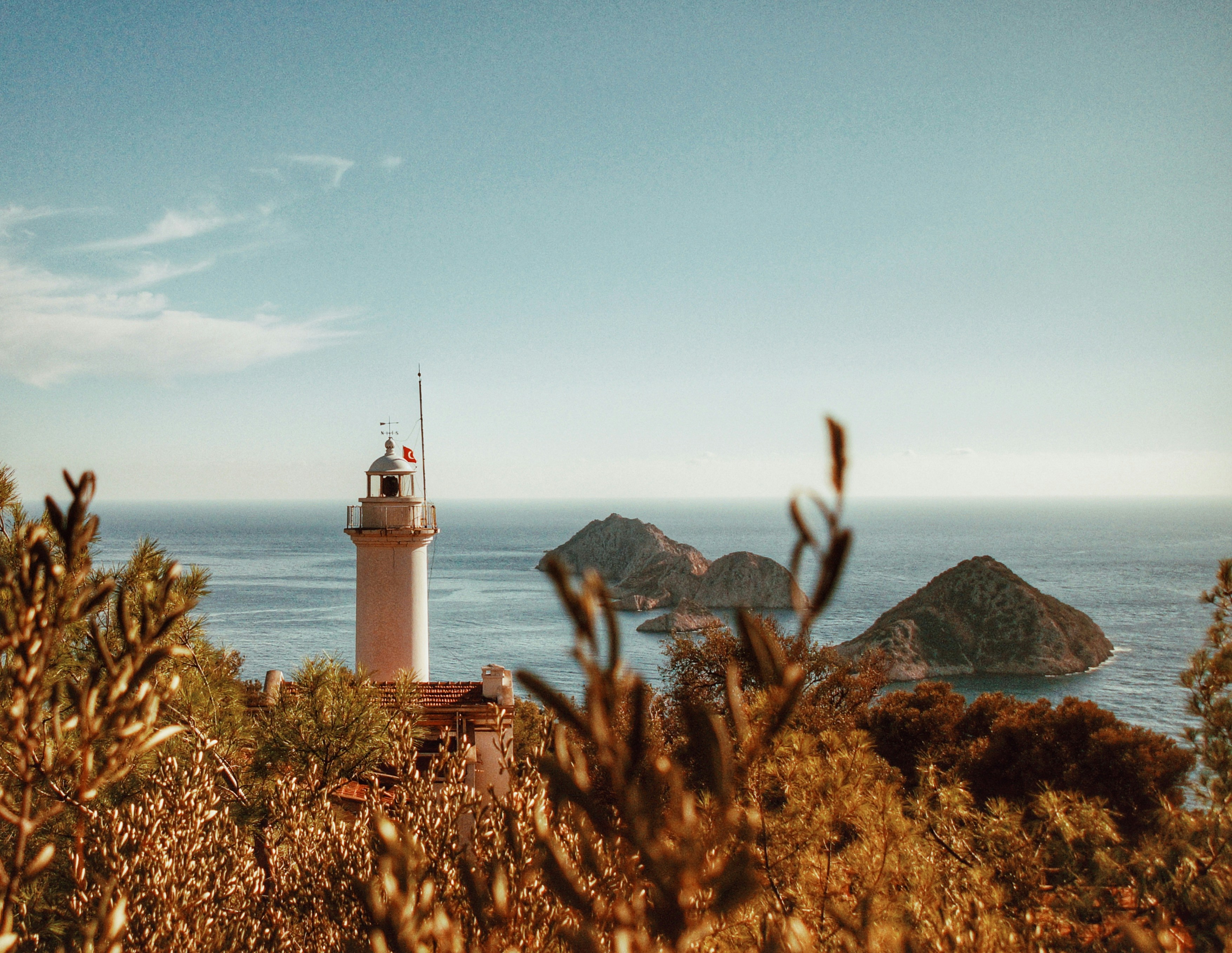 A light house sitting on top of a lush green hillside photo – Free ...