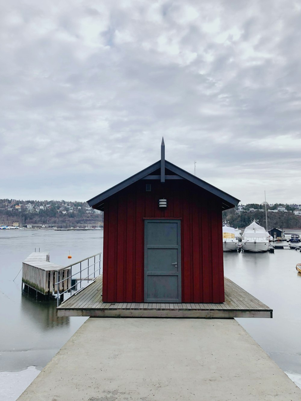 a red building sitting on top of a pier next to a body of water