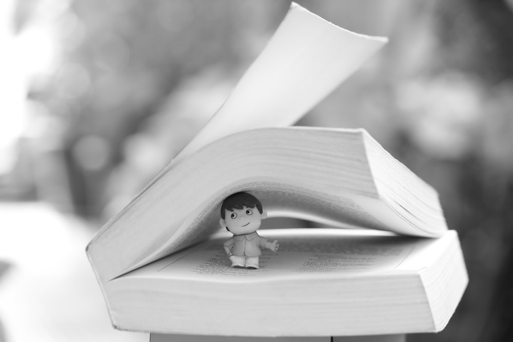 a small figurine sitting on top of an open book
