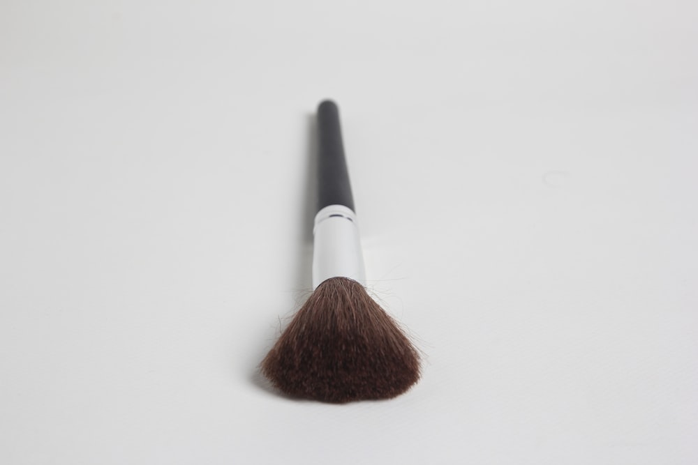 a makeup brush on a white surface