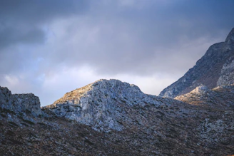 Time-lapse style image of clouds moving over a rugged mountain range, highlighting environmental beauty.