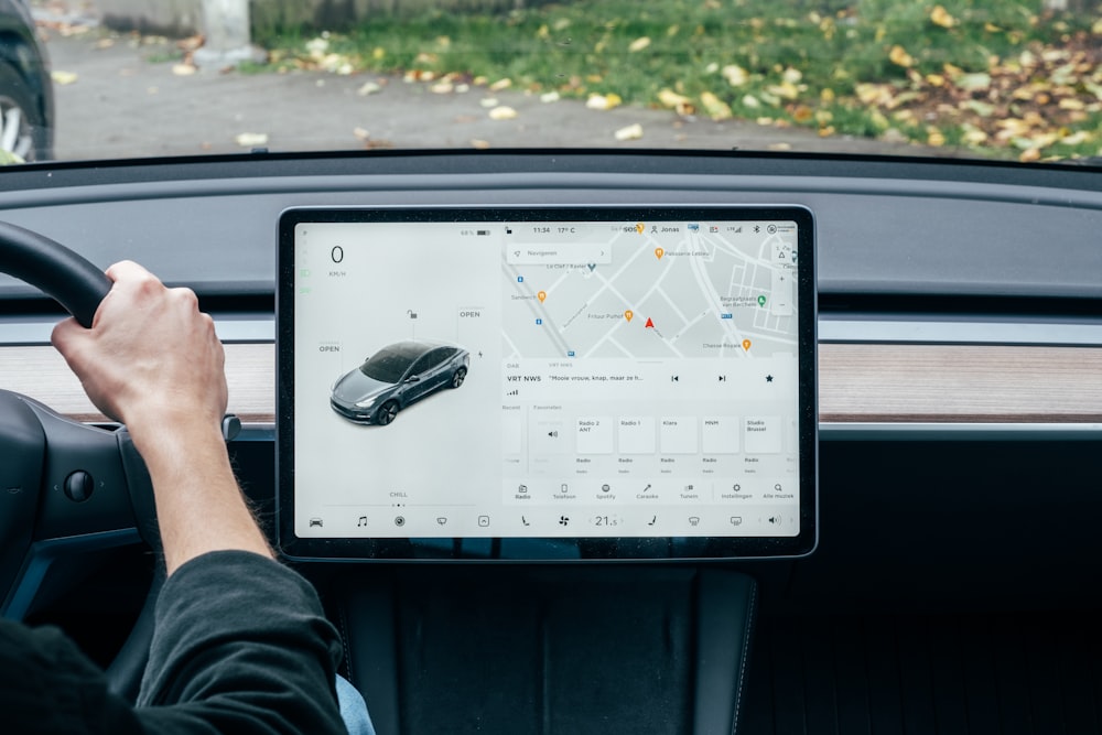 a person driving a car with a computer on the dashboard