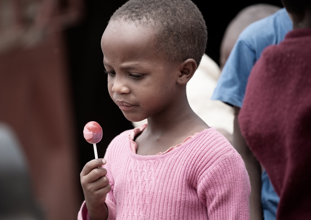 a little boy holding a candy lollipop in his hand