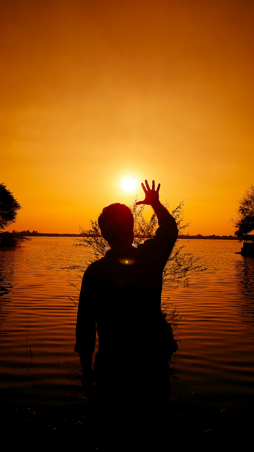 a person standing in a body of water at sunset