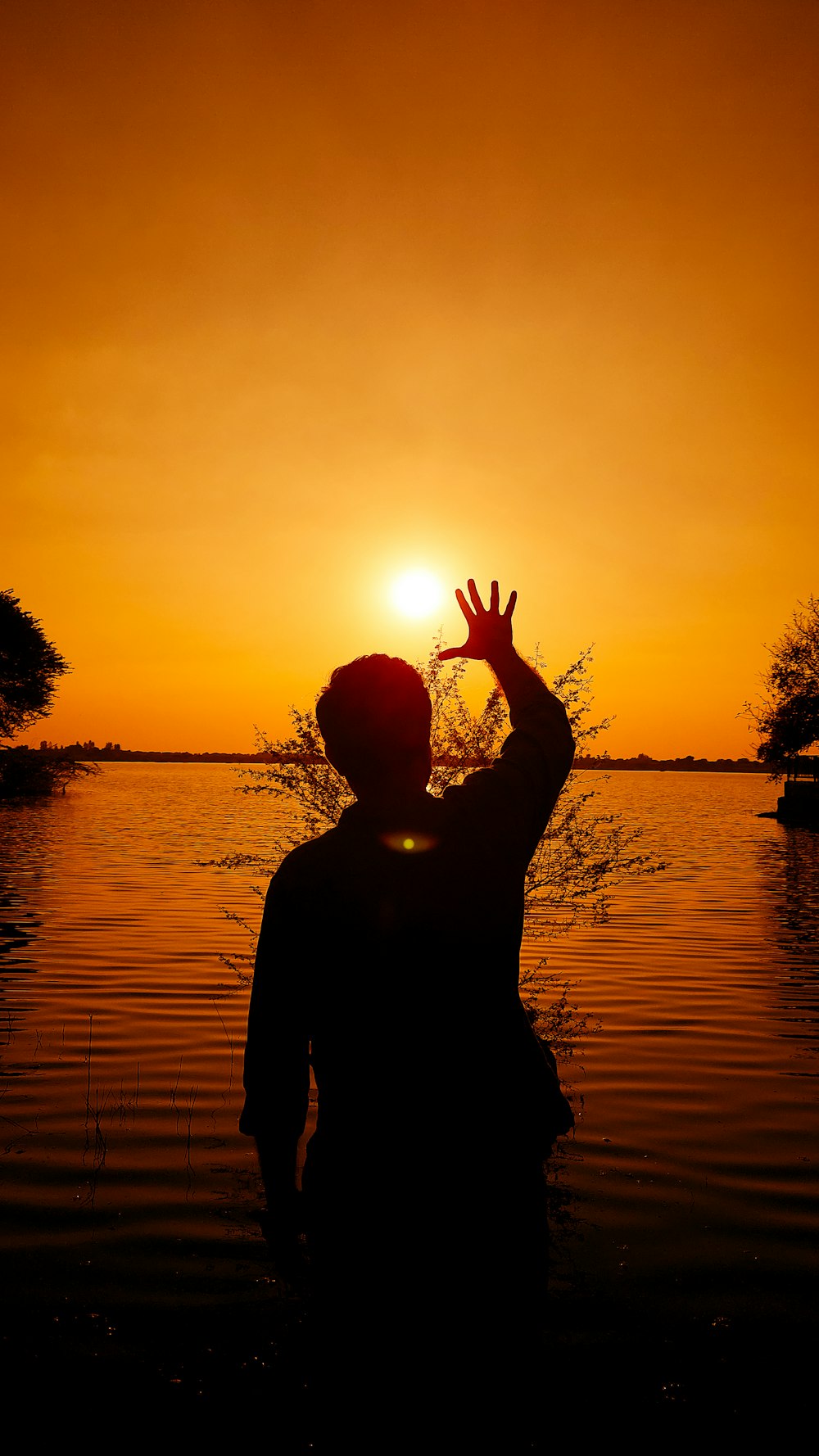 une personne debout dans un plan d’eau au coucher du soleil