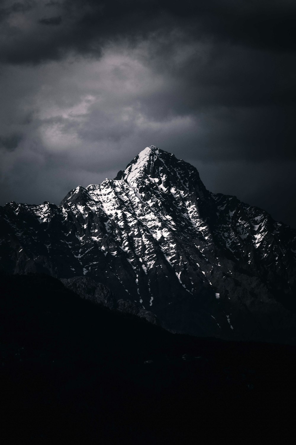 a large mountain covered in snow under a cloudy sky