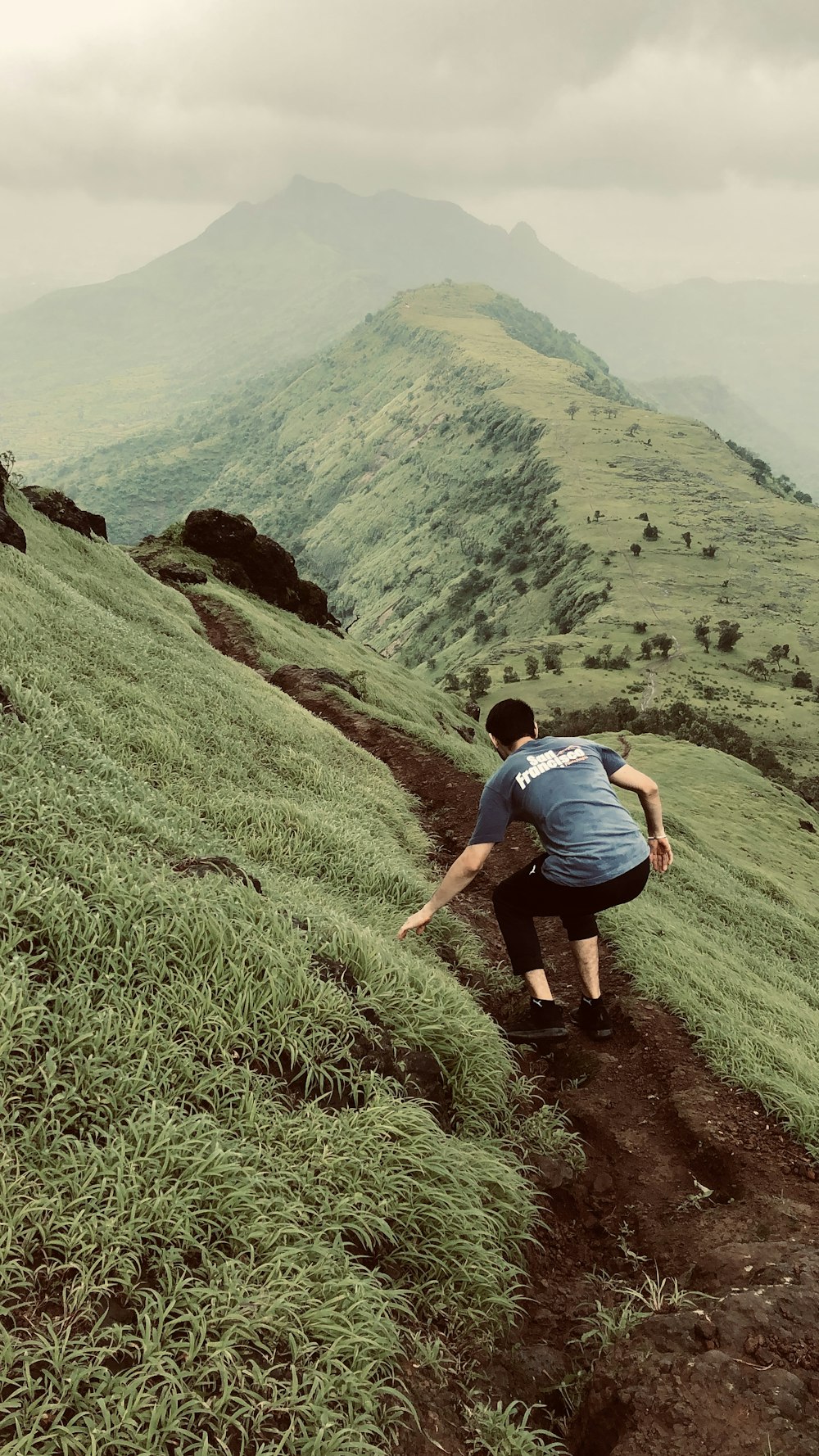 a man climbing up a grassy hill in the mountains