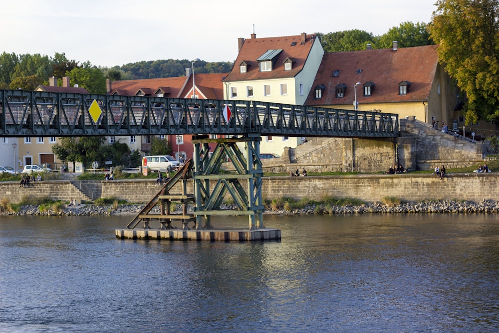 a bridge over a body of water with houses in the background