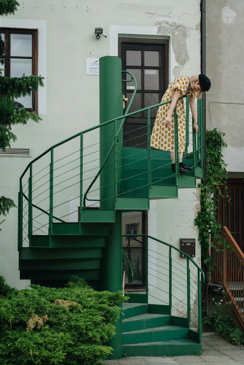 a woman standing on a green staircase next to a building