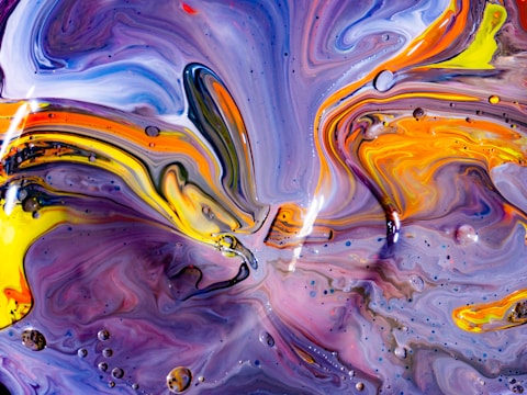 Close-up of swirling colors merging on a canvas.