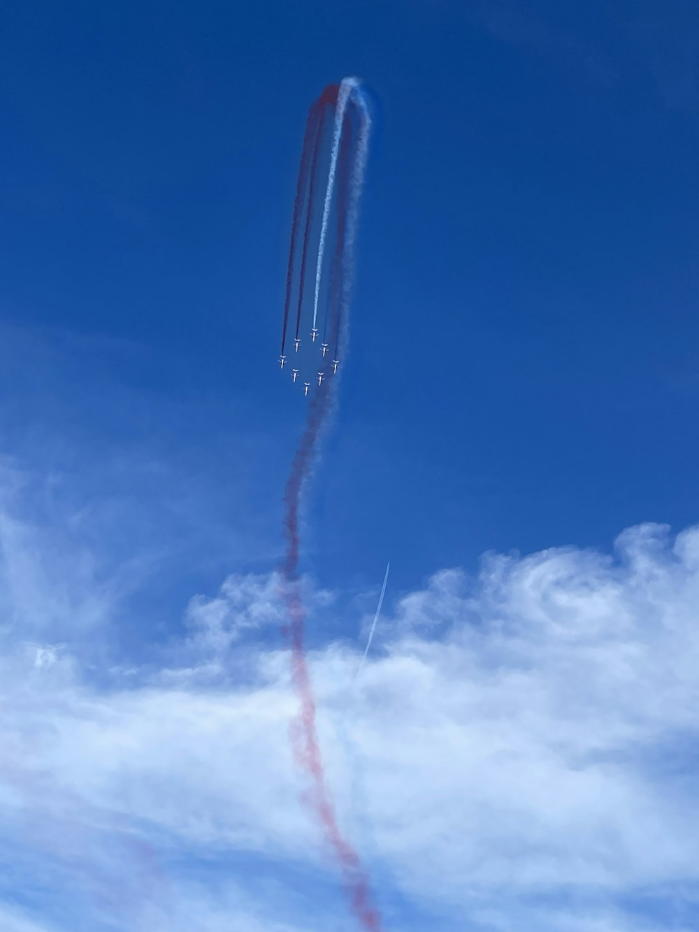 a red and white contrail flying through a blue sky