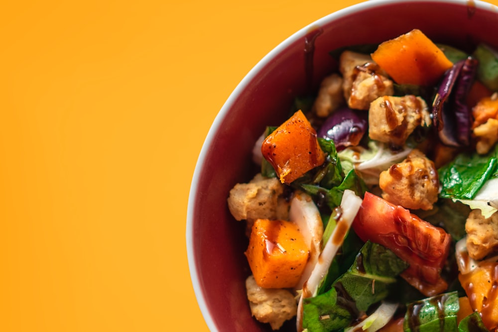 a red bowl filled with meat and vegetables