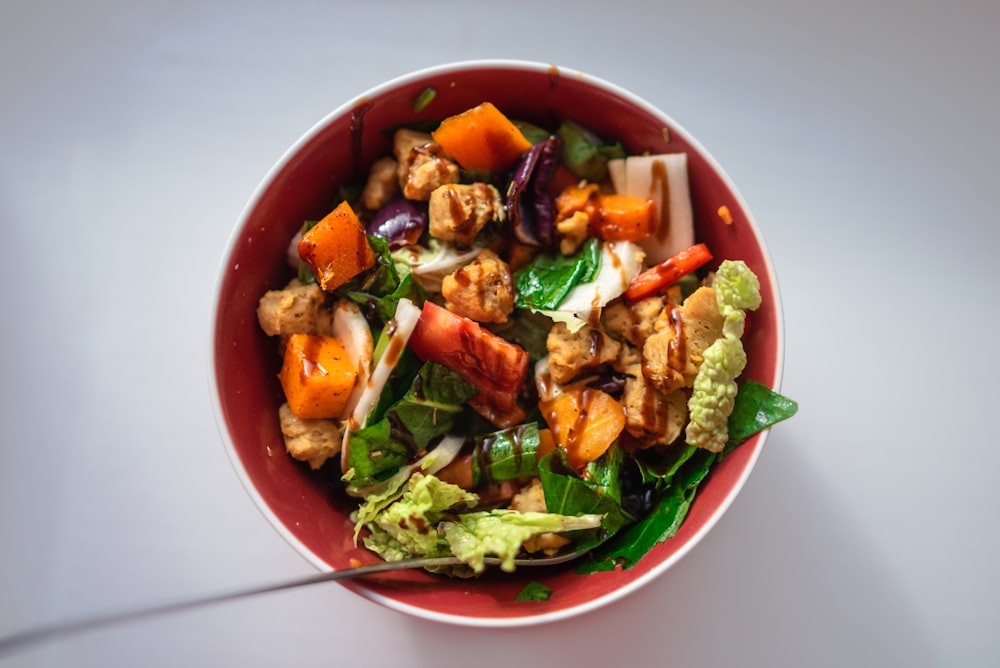 a red bowl filled with meat and vegetables