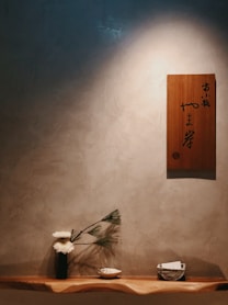 a wooden shelf with a vase and flowers on it