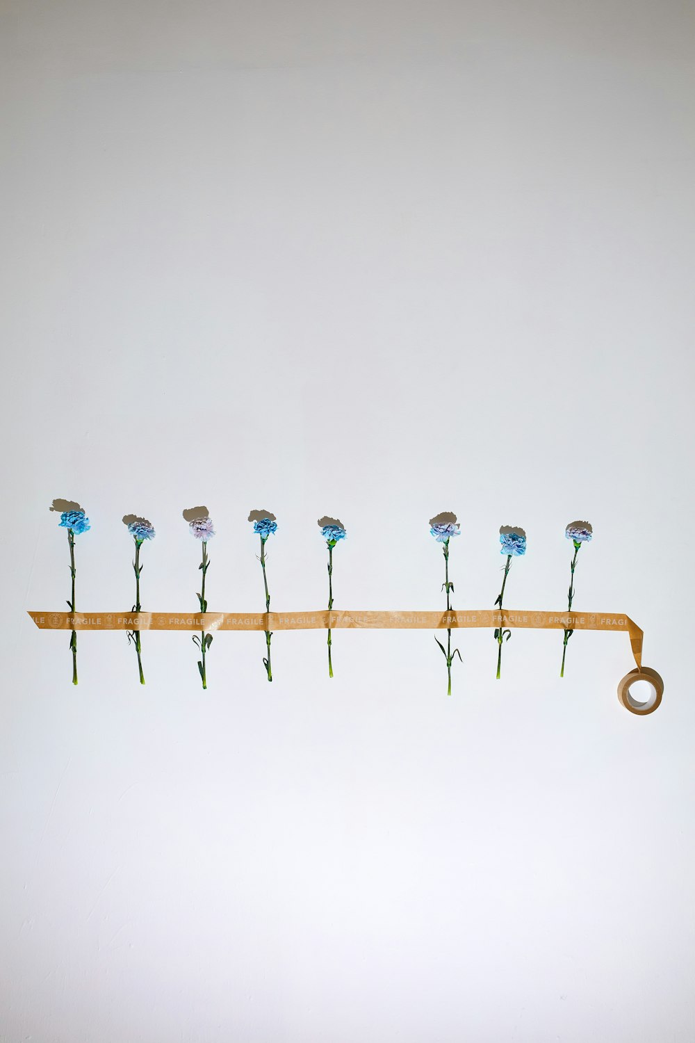 a row of blue flowers sitting on top of a wooden shelf