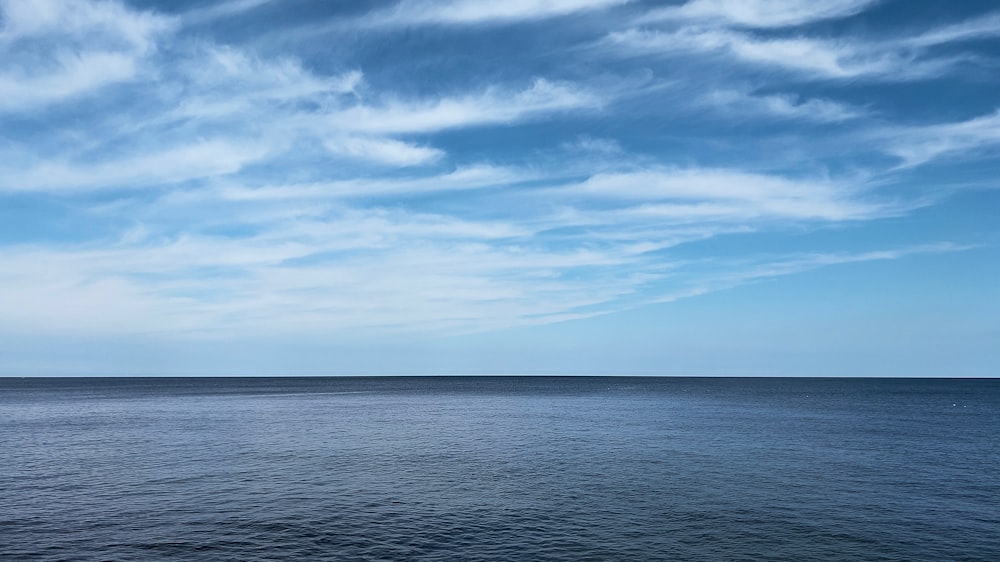 a large body of water under a cloudy blue sky