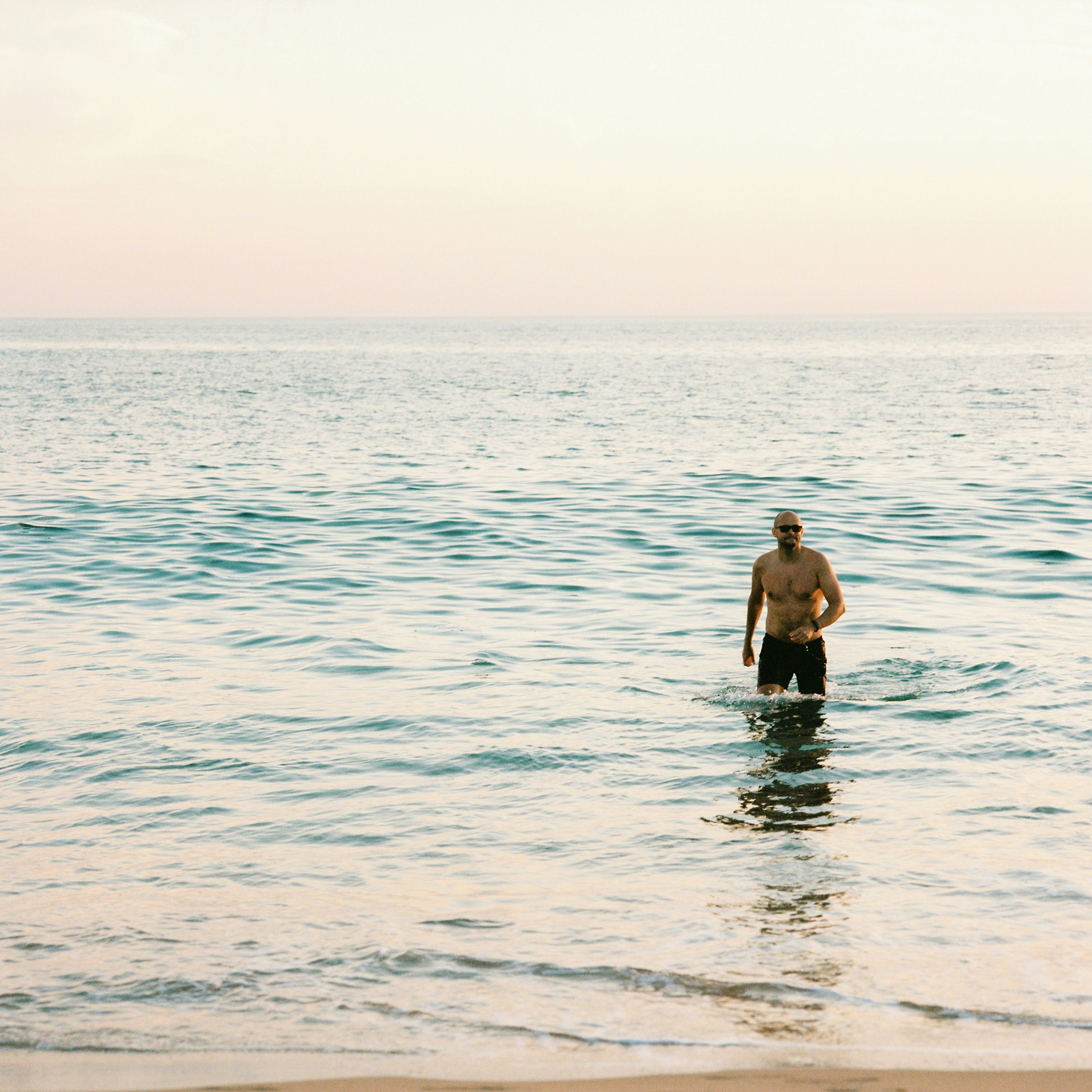 Ein Mann steht mit einem Surfbrett im Meer