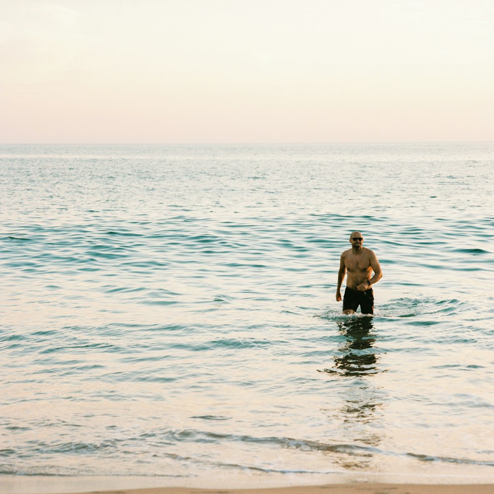 a man standing in the ocean with a surfboard