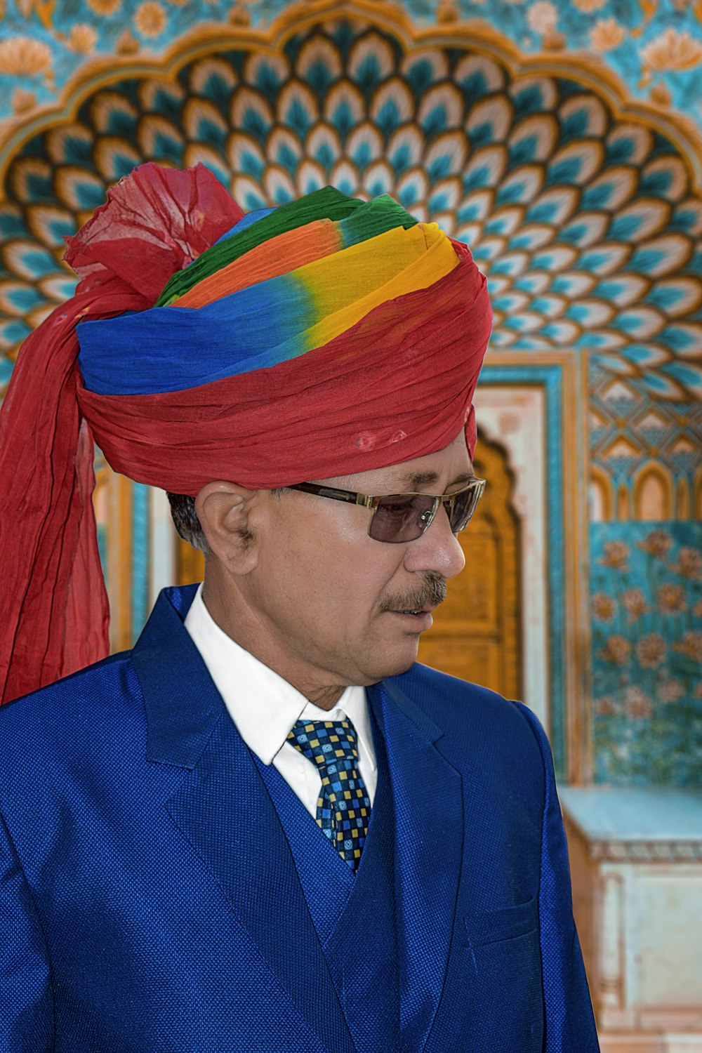 a man in a blue suit with a red turban