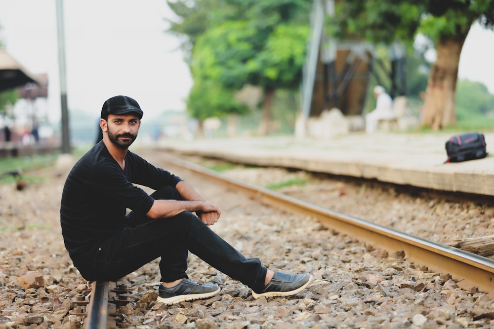 a man is sitting on the railroad tracks
