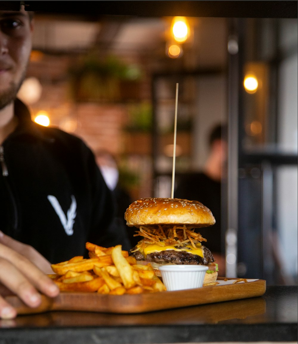 a man sitting at a table with a hamburger and french fries