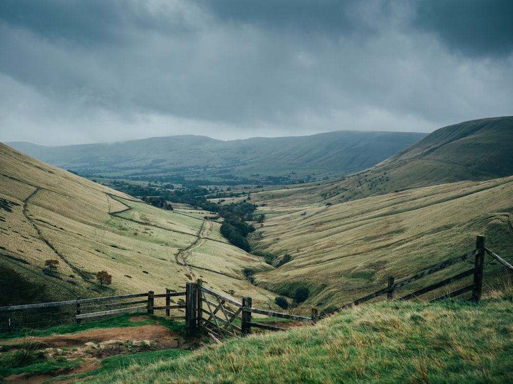 a view of a valley with a wooden fence in the foreground