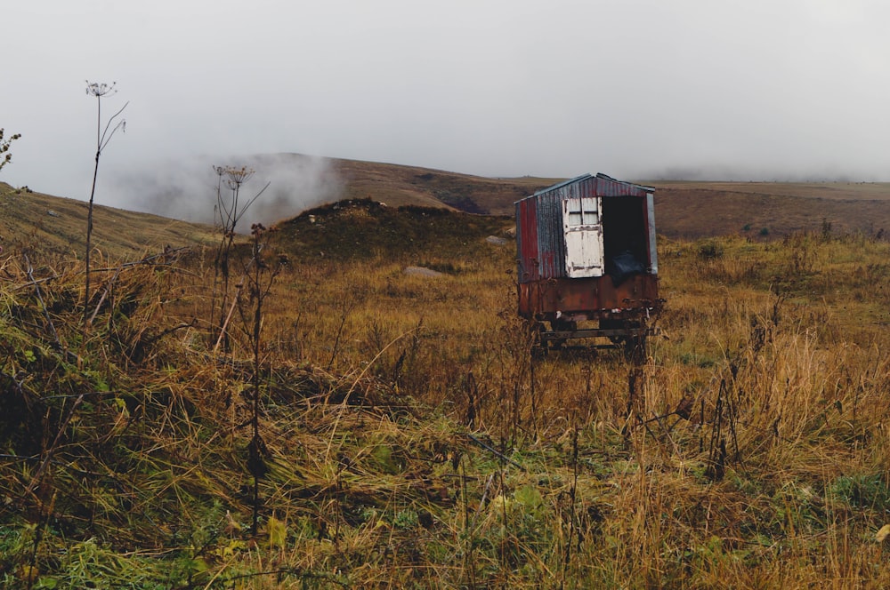 an outhouse in the middle of a grassy field