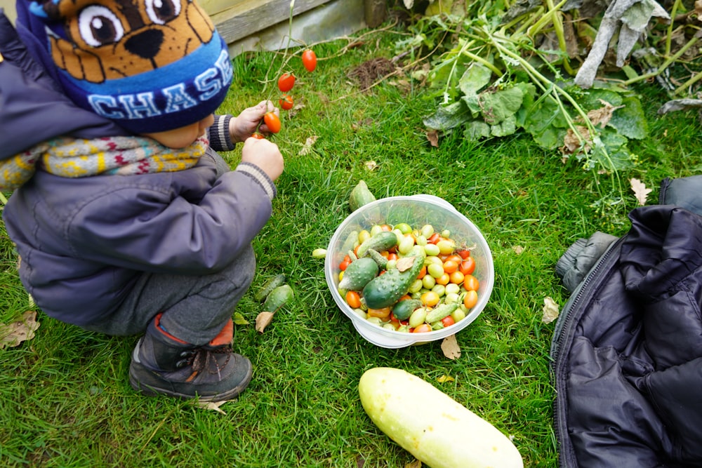 a child in a blue hat is eating vegetables