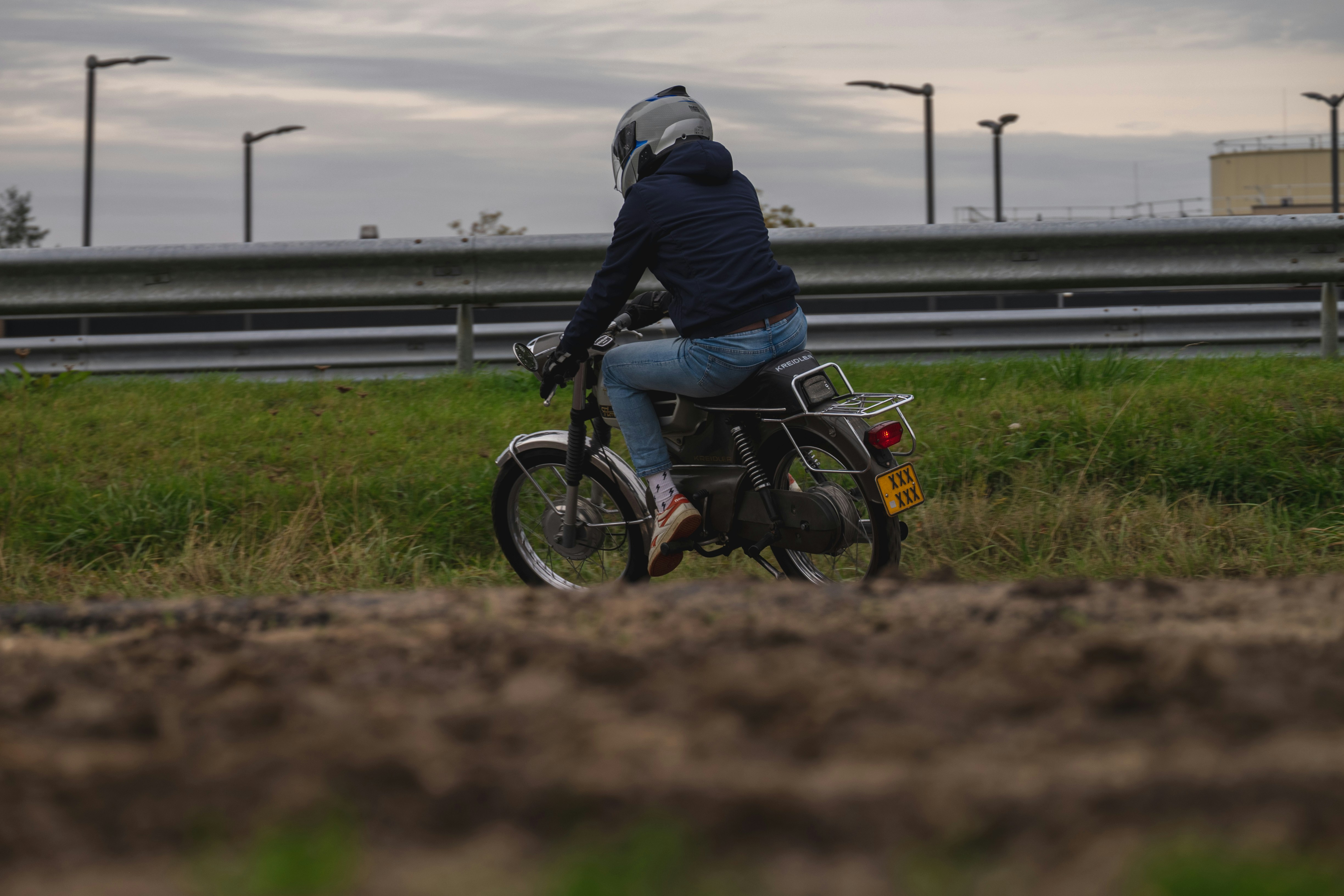 ein mann, der mit einem motorrad eine unbefestigte straße hinunterfährt