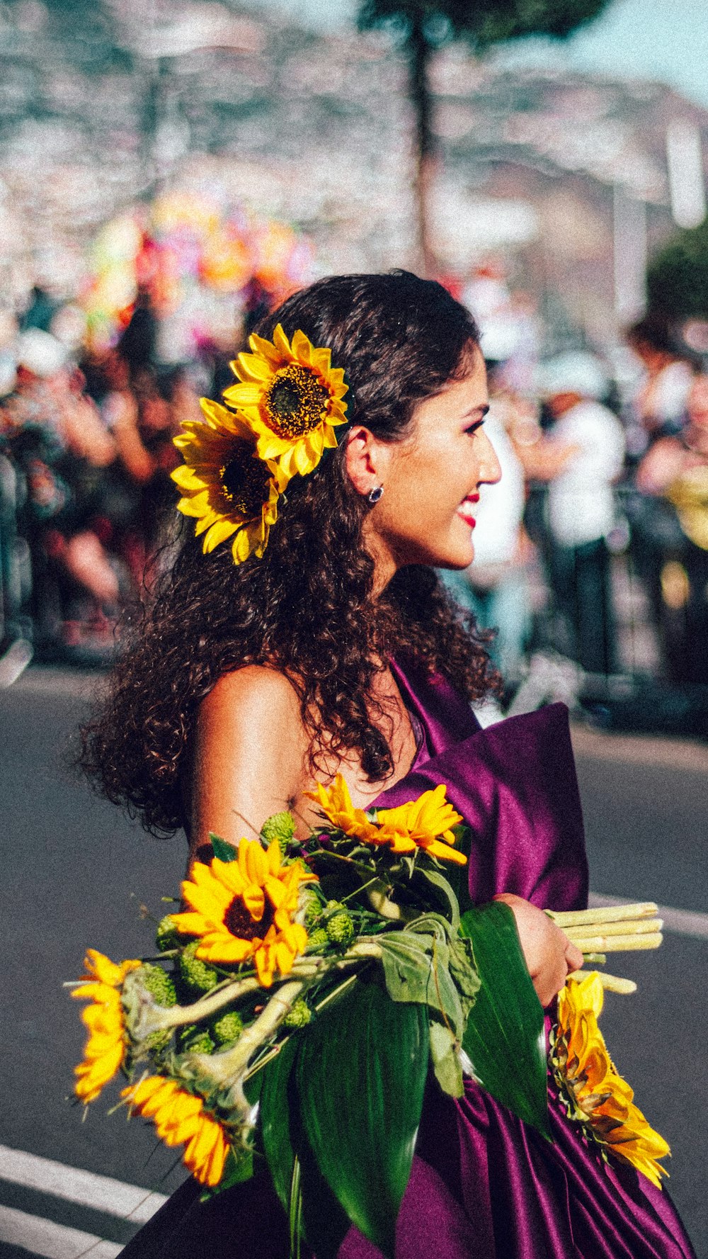 a woman in a purple dress holding a bouquet of sunflowers