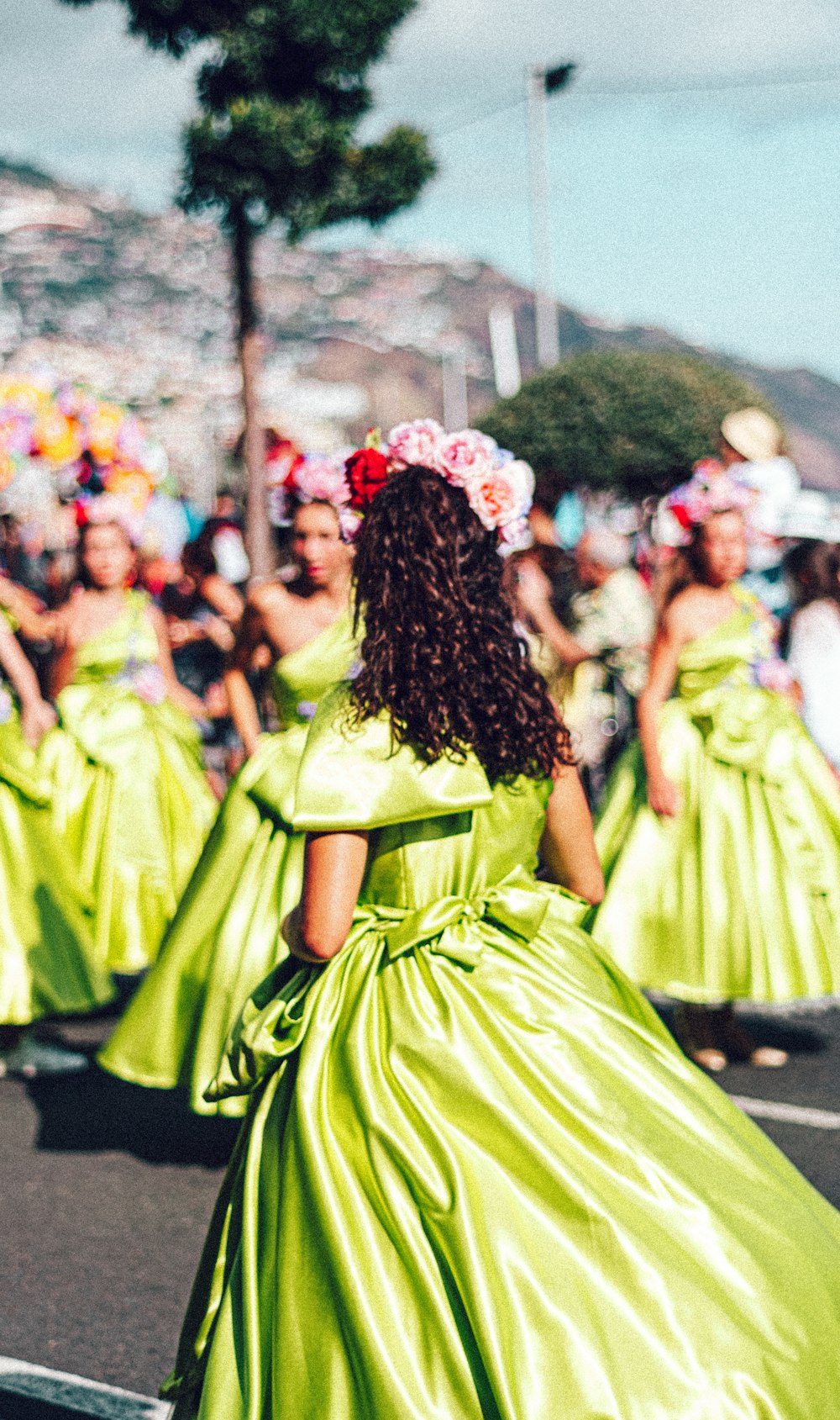 a group of women in green dresses walking down a street