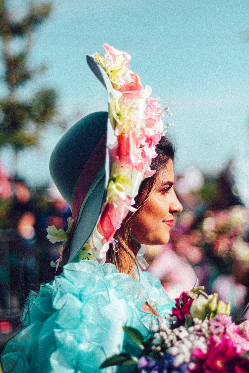 a woman wearing a hat and holding a bouquet of flowers