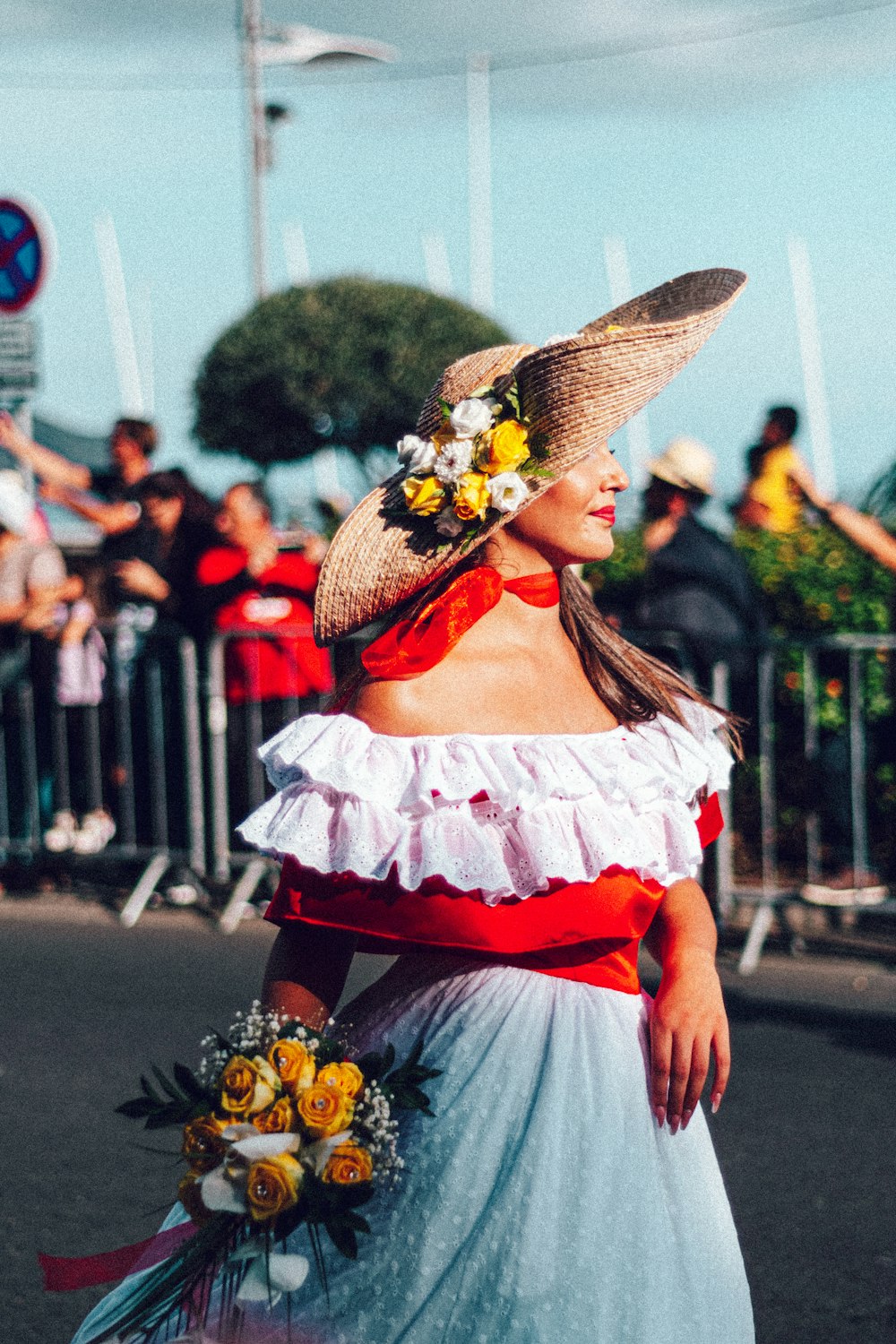 a woman in a dress and hat walking down the street