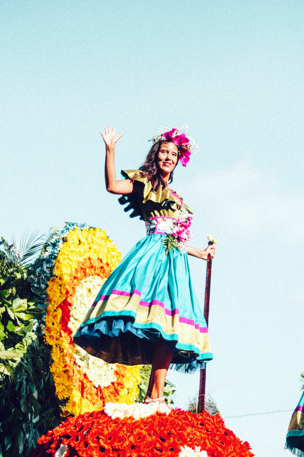 Eine Frau in einem blauen Kleid steht auf einem Festwagen