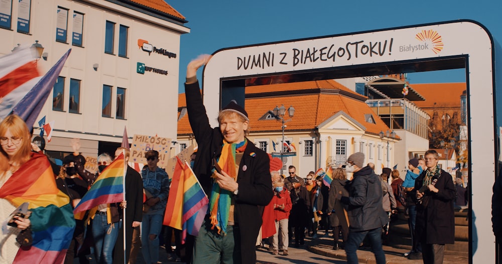 Un uomo che tiene una bandiera arcobaleno di fronte a una folla di persone