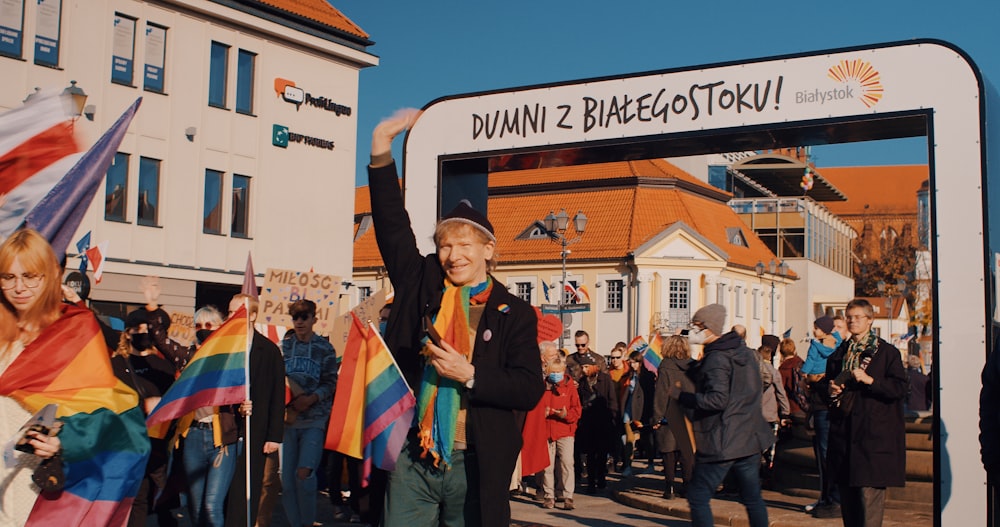 Un homme tenant un drapeau arc-en-ciel devant une foule de gens