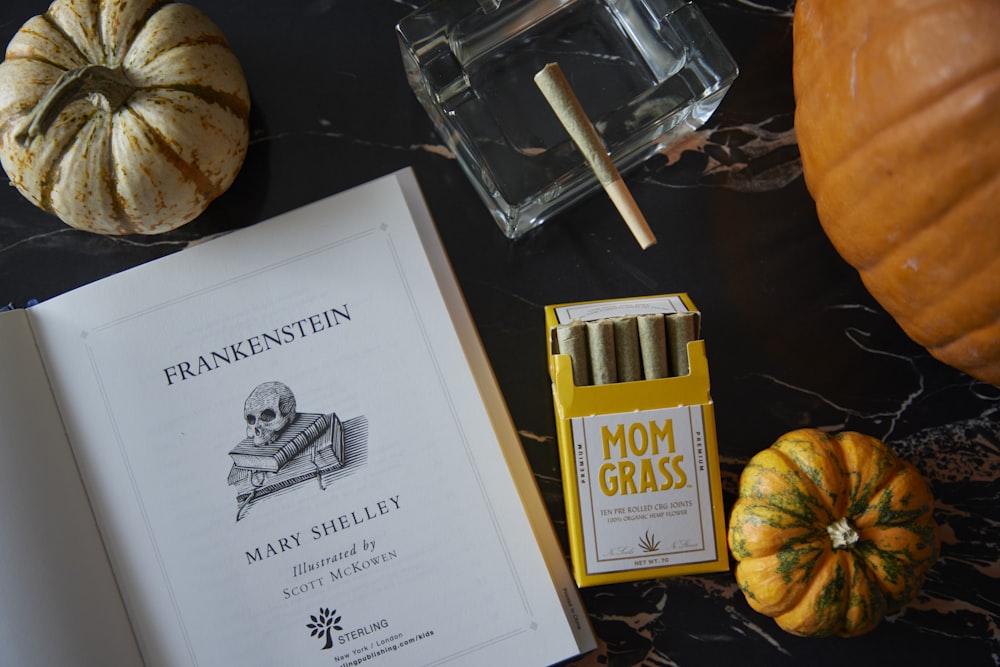 an open book sitting on top of a table next to two pumpkins