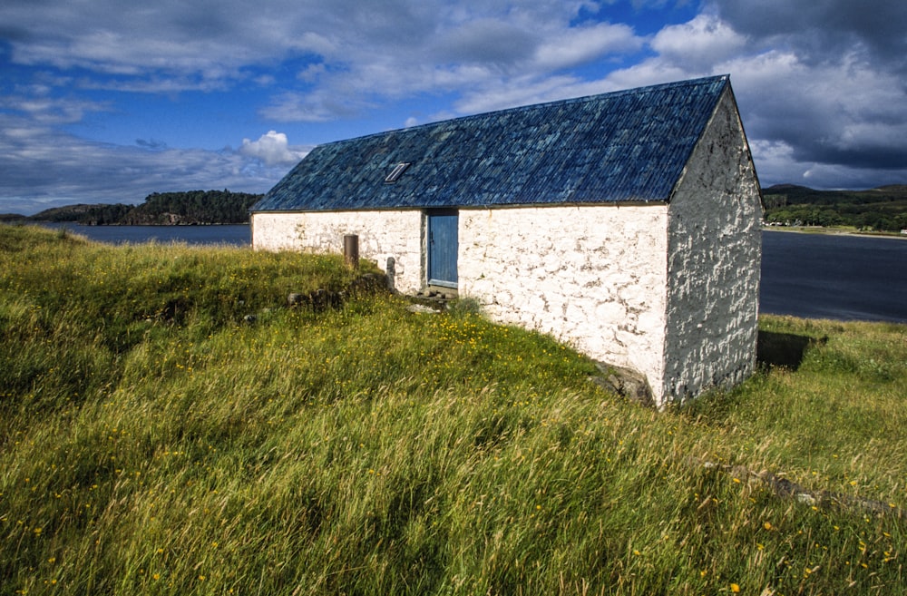 a small white building sitting on top of a lush green field